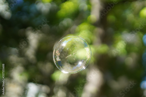 Soap bubble in the air with reflections. On blurred background © Alex