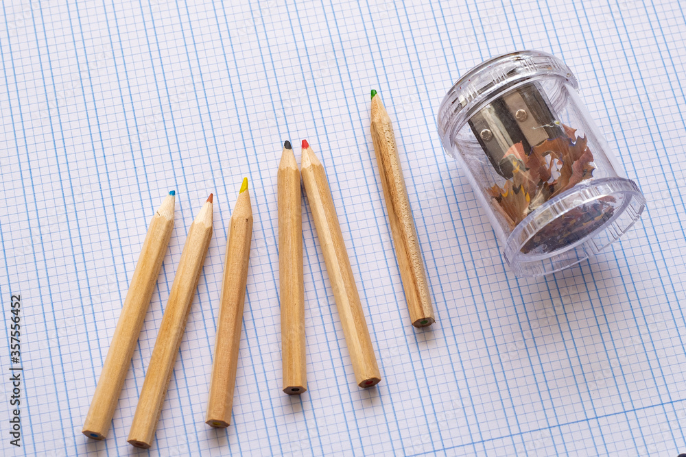 Back to school. Vintage wooden simple pencils on squared paper. On the side is a pencil sharpener.