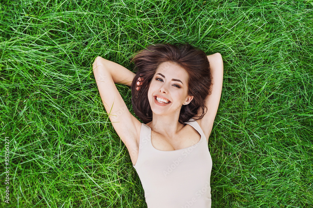 Relaxing laughing woman lying on summer meadow. Smiling girl resting in park. Enjoy life, having fun, leisure, relaxation, summer, people, lifestyle concept Relaxing laughing woman lying on summer meadow. Smiling girl resting in park. Enjoy life, having fun, leisure, relaxation, summer, people, lifestyle concept