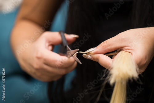 Preparing a strand of hair for extension. Hair and hair tools close-up.