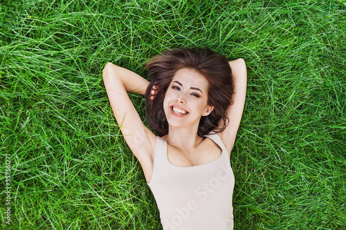 Relaxing laughing woman lying on summer meadow. Smiling girl resting in park. Enjoy life, having fun, leisure, relaxation, summer, people, lifestyle concept