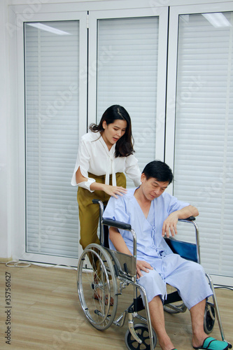 Thai woman is Caring and Take the old father sitting on wheelchair and ill health for to see a doctor at hospital in Thailand