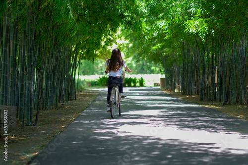 A young female tourist cycling alone in a bamboo garden