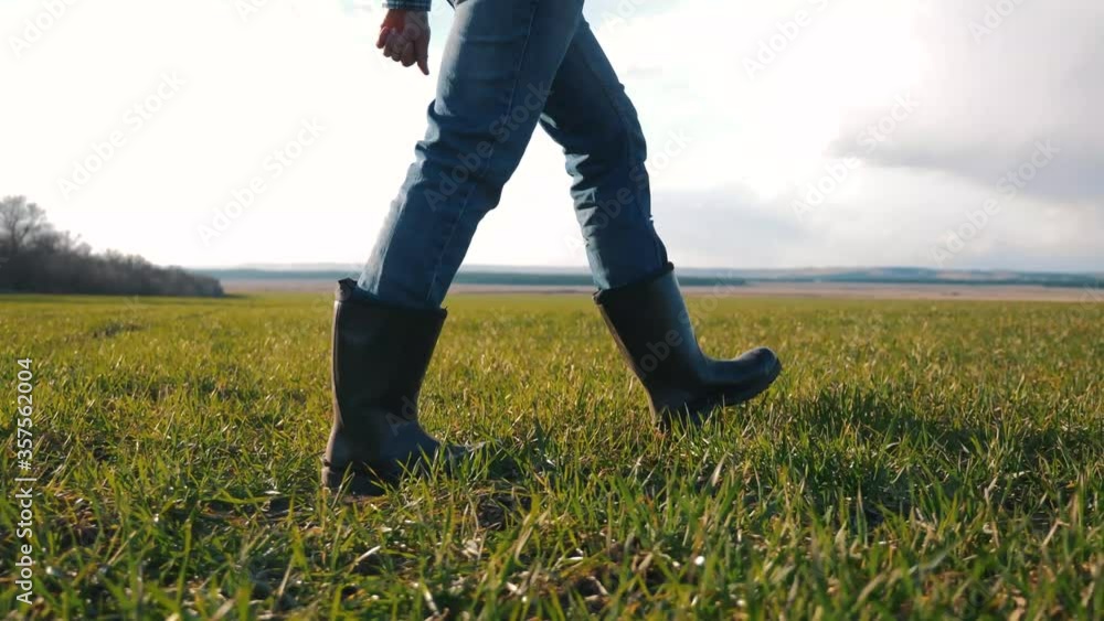 Walking a male farmer on a greenfield. The farmer's feet in boots Walking a male farmer on a greenfield. The farmer's feet in boots
