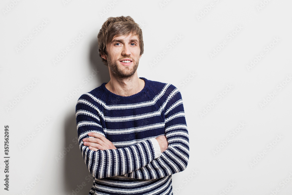 Portrait of handsome smiling young man with folded arms. Smiling joyful cheerful men with crossed hands studio shot. Isolated on gray background Portrait of handsome smiling young man with folded arms. Smiling joyful cheerful men with crossed hands studio shot. Isolated on gray background