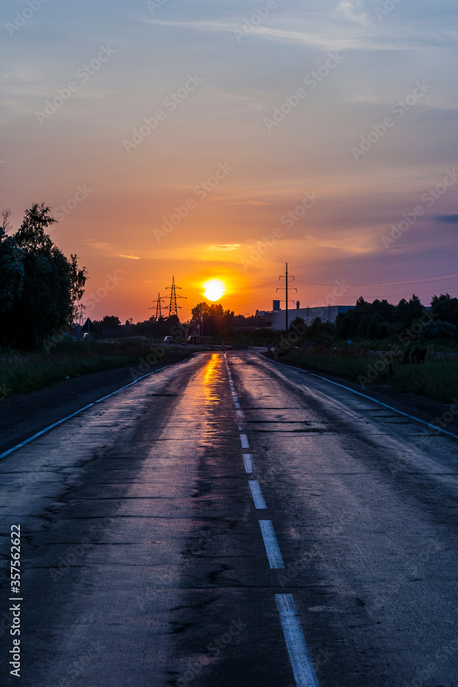 Sunset above an old long bumpy asphalt road with copy space