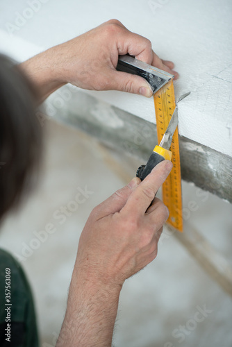Styrofoam, seiling mounting. A man cuts foam. Warming. Repair in the house. DIY repair. Work with polystyrene foam, insulation of walls and ceiling