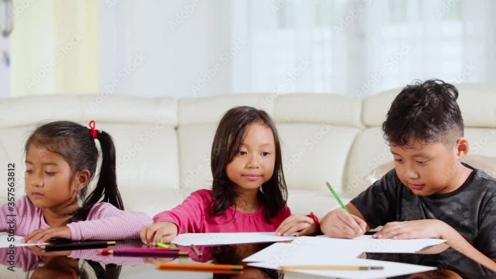 Group of happy kids coloring a paper on the table Group of happy kids coloring a paper on the table