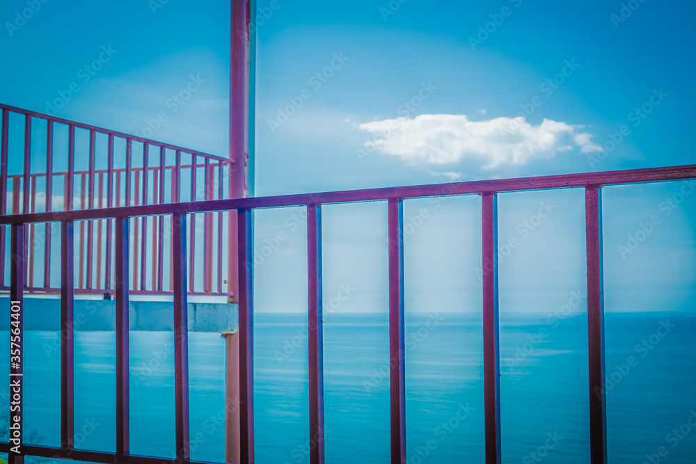 Metal grille fencing against the blue sky. Observation terrace on a background of blue sea. Playground in a mountain hotel. Spring. Georgia. Metal grille fencing against the blue sky. Observation terrace on a background of blue sea. Playground in a mountain hotel. Spring. Georgia.