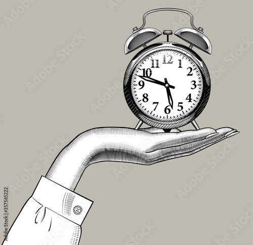 Engraved drawing of a female hand holding on the palm a retro alarm clock