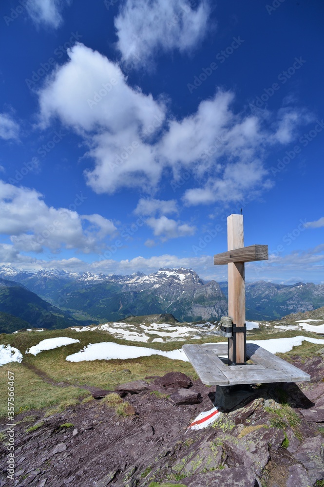 Wooden summit cross in the Glarus Alps on a sunny day in Switzerland