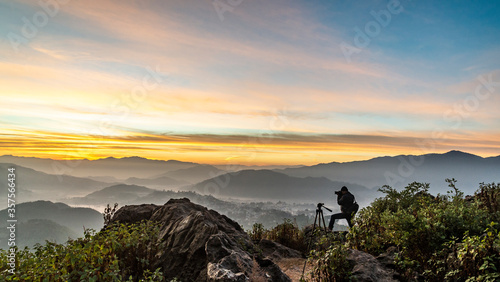 Fotografía A Photographer in action during sunrise in the mountains