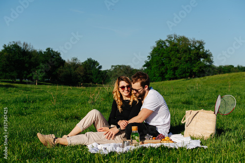 Couple in love having a picnic in a countryside on a green grass.