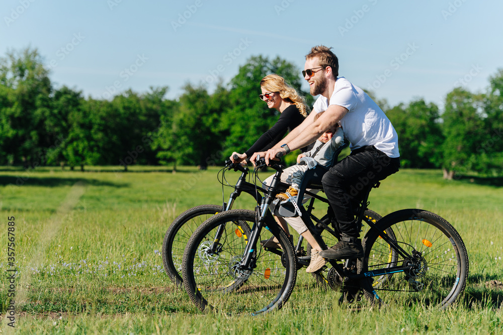 Cheerful family riding along sunlit trees and fields