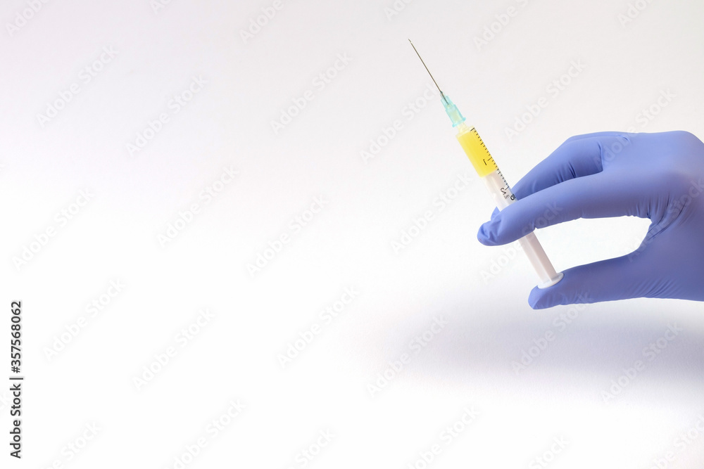 A hand in a blue latex medical glove holds a needle with medicine injection, antibiotic or vaccine. White background, save the space. Vitamin Injections A hand in a blue latex medical glove holds a needle with medicine injection, antibiotic or vaccine. White background, save the space. Vitamin Injections