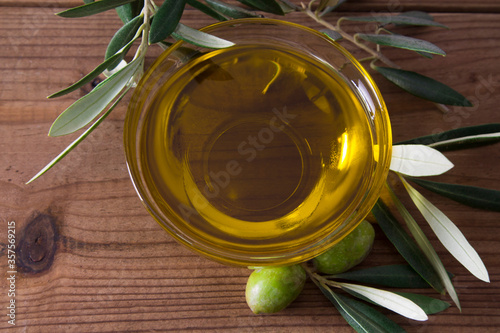 glass vessel with extra virgin olive oil and olives with branch