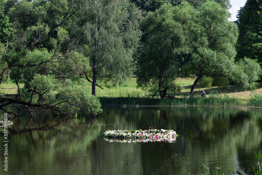 The celebration of Ivan Kupala (St. John Day). Old holiday dedicated to the summer solstice. Traditional huge wreath of fresh flowers on the water. Selective focus.