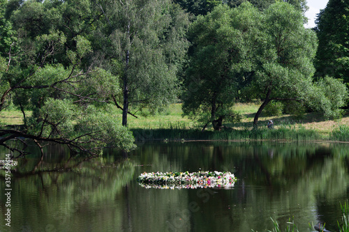 The celebration of Ivan Kupala (St. John Day). Old holiday dedicated to the summer solstice. Traditional huge wreath of fresh flowers on the water. Selective focus. photo