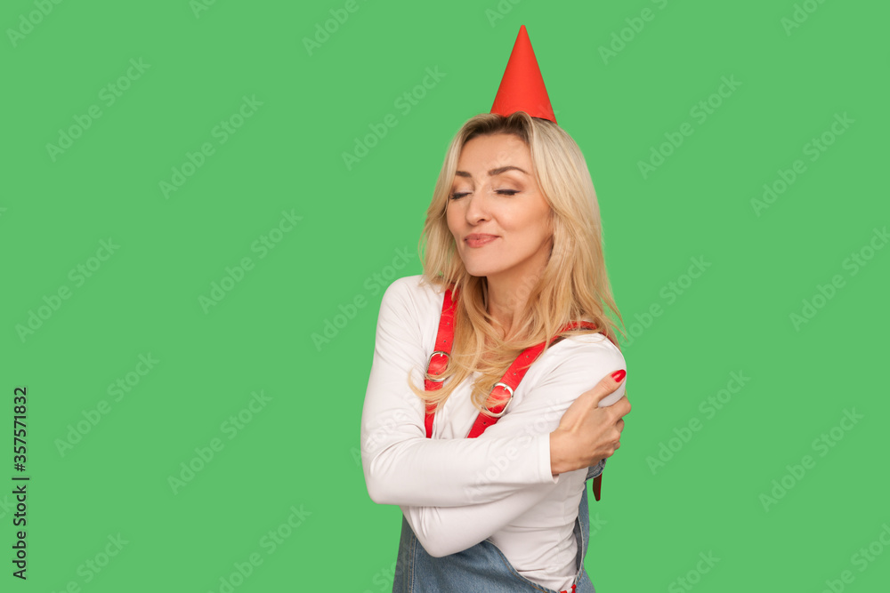 Φωτογραφία Happy birthday to me! Portrait of egoistic selfish adult woman with party cone on head embracing herself and smiling with pleased expression, self love concept