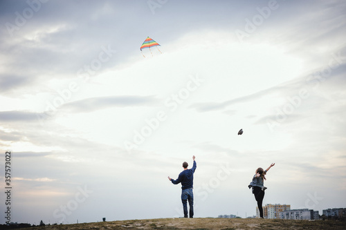 A young family launches an air kite on the edge of the city. Place for text on the sky background