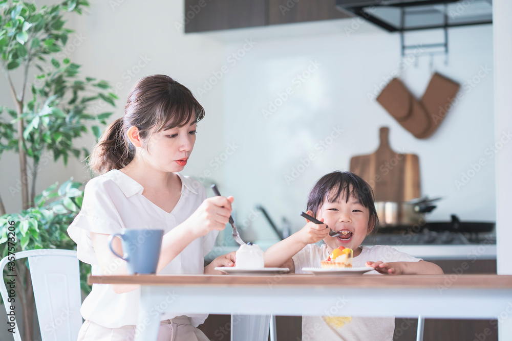 Fototapeta premium 部屋のテーブルでケーキを食べる親子