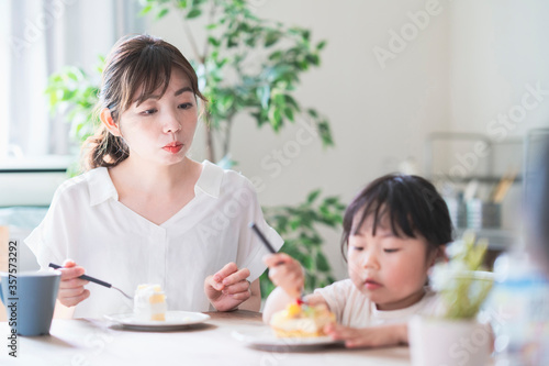 部屋のテーブルでケーキを食べる親子
