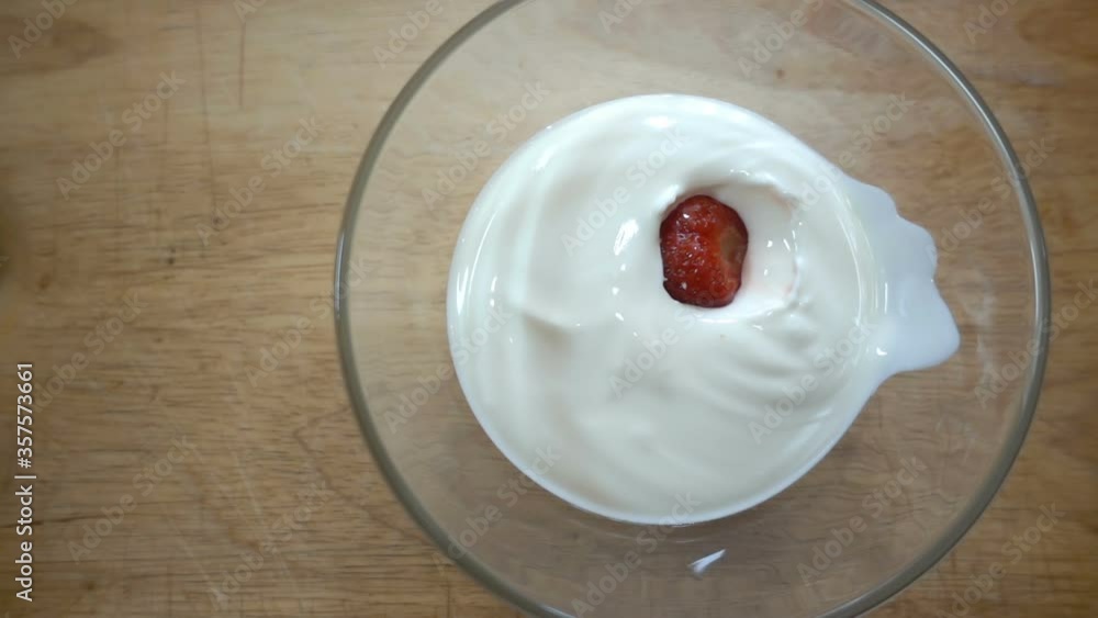 Strawberrie fall in slow motion in a bowl with sour cream Strawberrie fall in slow motion in a bowl with sour cream