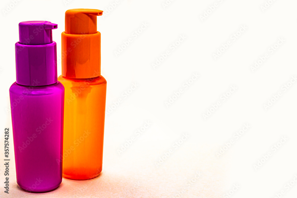 orange and pink plastic bottles for cosmetics isolate close-up orange and pink plastic bottles for cosmetics isolate close-up