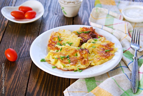 Potato fritters on a white plate on a wooden background.