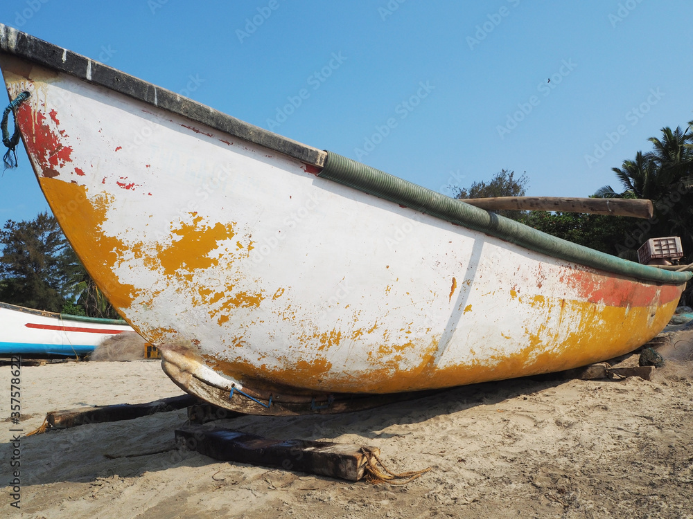Bottom view of an old battered fishing wooden boat standing on a sandy beach. Bottom view of an old battered fishing wooden boat standing on a sandy beach.