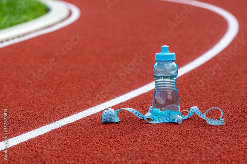 Bottle of water with measure tape on running track photo