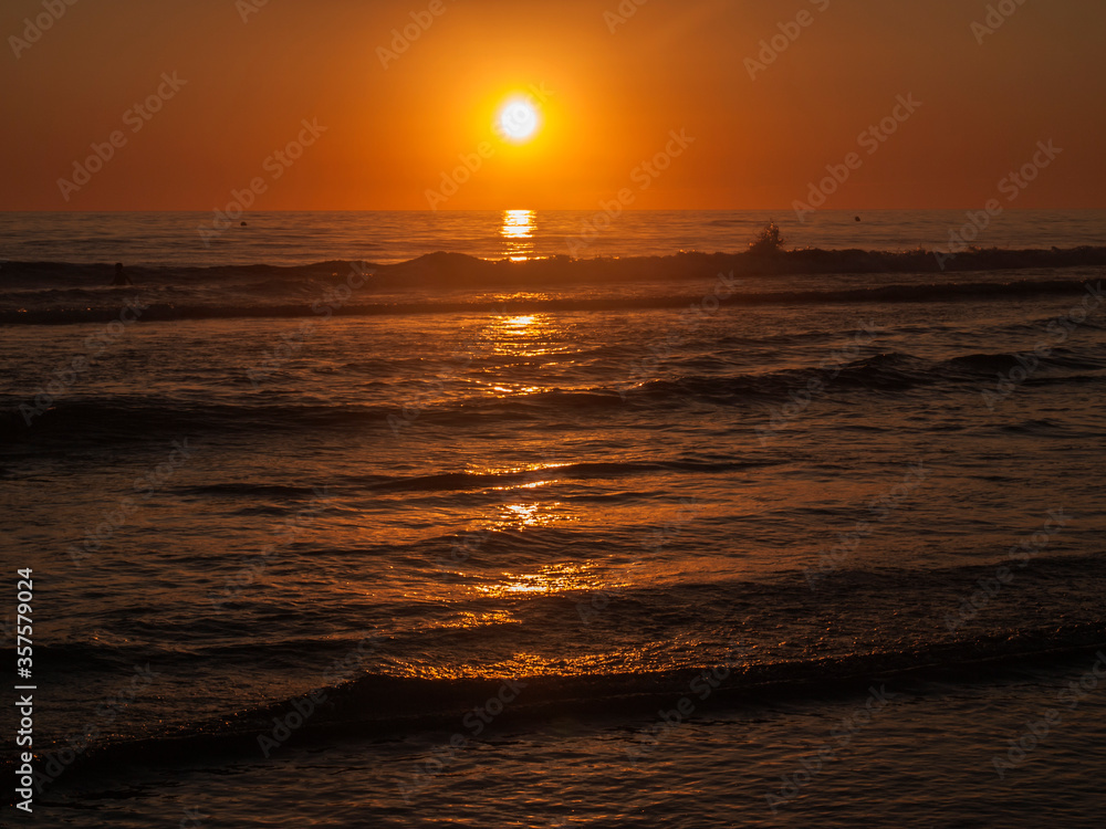 Sunset with reflections in the sand at Zahora beach in summer, Cadiz, Andalusia, Spain