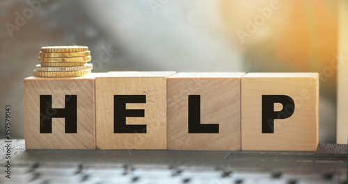 Help - text on wooden cubes puton computer keyboard with stack of coins. Donation and charity concept. Business startup concept photo