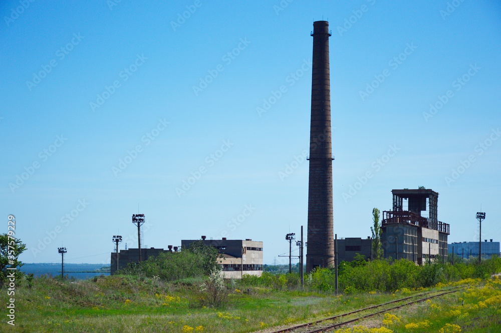 buildings and chimney of an abandoned factory. abandoned factory on the outskirts of the city. visible remaining workshops and chimney buildings and chimney of an abandoned factory. abandoned factory on the outskirts of the city. visible remaining workshops and chimney