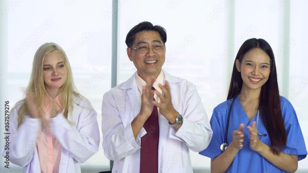 senior doctor and caucasian and asian medical students clapping hands to thank you medical team who develop new drug and vaccine. healthcare and medical concept senior doctor and caucasian and asian medical students clapping hands to thank you medical team who develop new drug and vaccine. healthcare and medical concept
