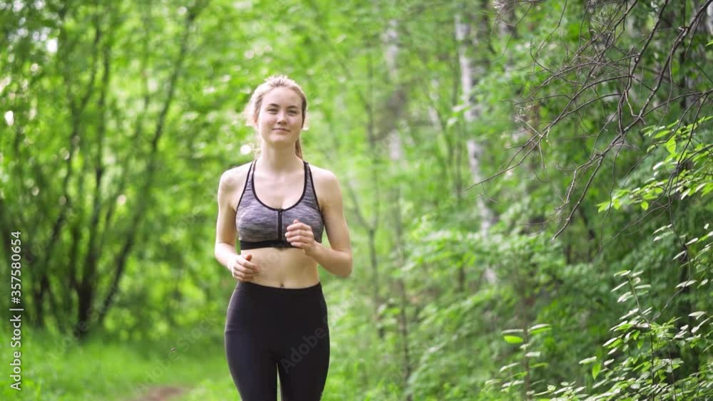 Slender sexy woman goes in for sports in the park. Morning run through the forest. Breasts sway while running Slender sexy woman goes in for sports in the park. Morning run through the forest. Breasts sway while running
