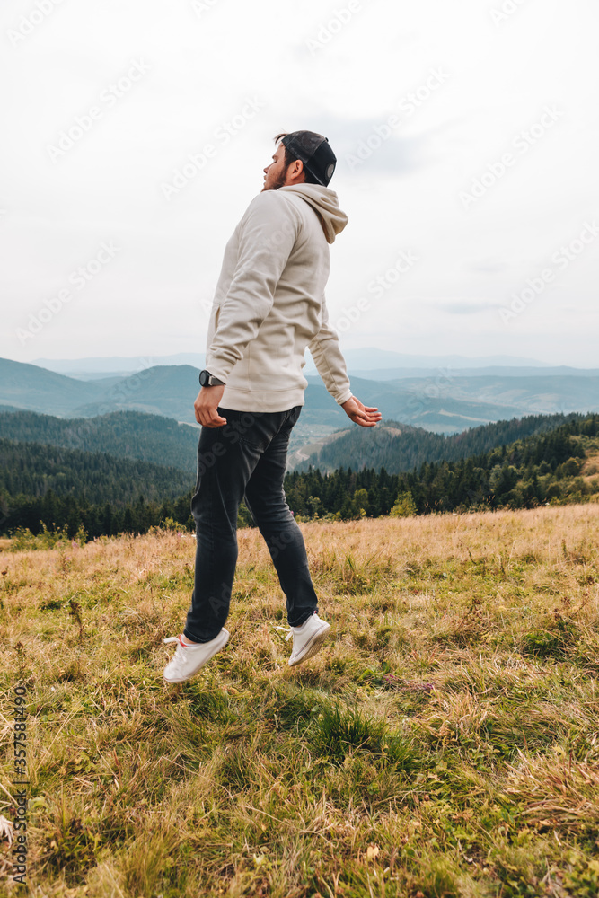 Fototapeta premium man with backpack happy jumping on the peak on the mount