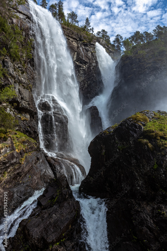 Obraz premium Hesjedalsfossen with blue sky and cascading water