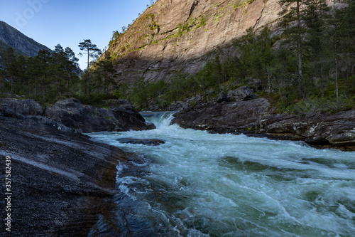 Waterfall in Norway with sun on a mountain in the background landscape
