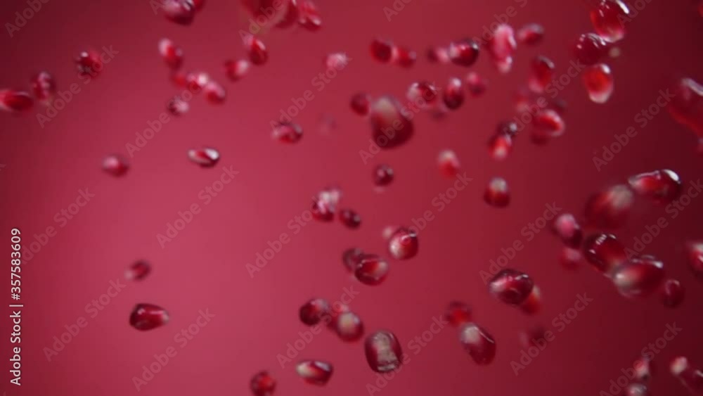 Juicy red grains of ripe pomegranate are flying diagonally on a red background in slow motion, loop footage Juicy red grains of ripe pomegranate are flying diagonally on a red background in slow motion, loop footage