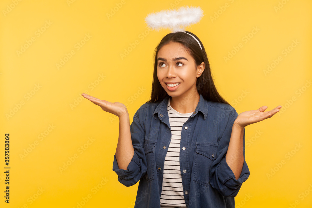 I am saint! Portrait of angelic girl with nimbus over head raising hands with blessing and glory gesture, looking up as if praying, smiling joyfully. indoor studio shot isolated on yellow background I am saint! Portrait of angelic girl with nimbus over head raising hands with blessing and glory gesture, looking up as if praying, smiling joyfully. indoor studio shot isolated on yellow background