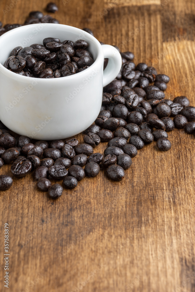 Top view of white cup with roasted coffee beans, on wooden table, horizontal, with copy space Top view of white cup with roasted coffee beans, on wooden table, horizontal, with copy space