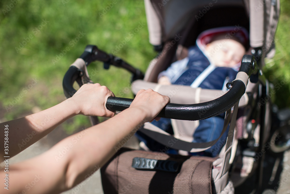 Young mother walking and pushing a stroller in the park