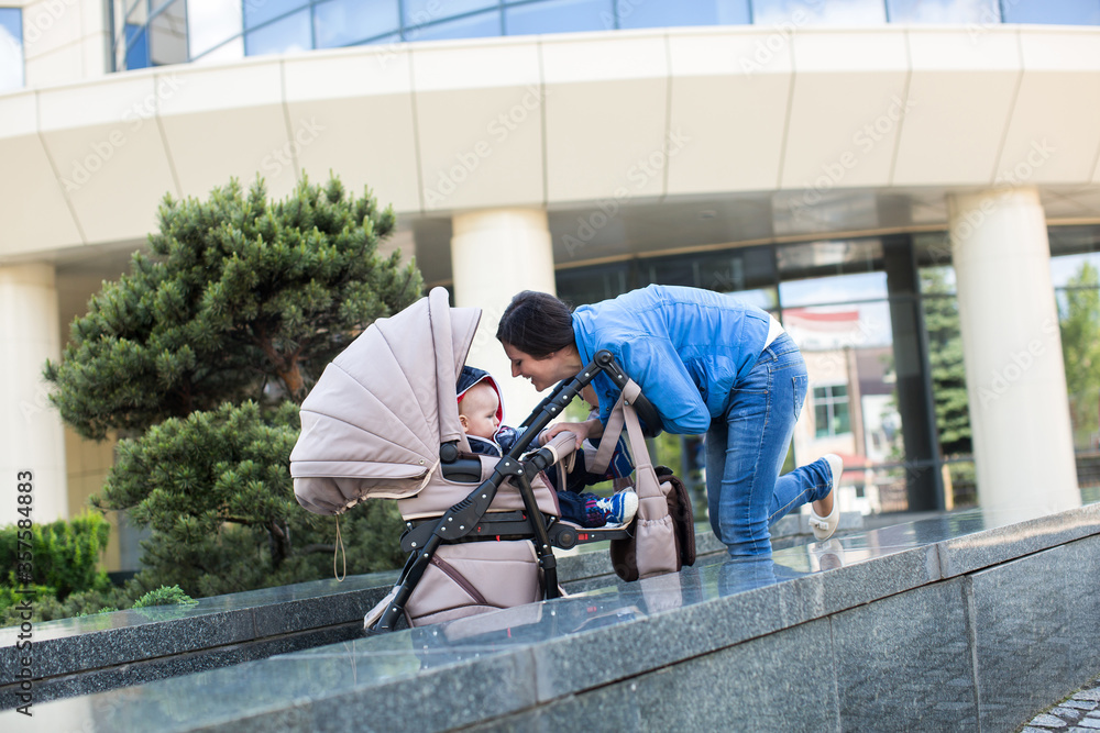 Young mother walking and pushing a stroller Young mother walking and pushing a stroller