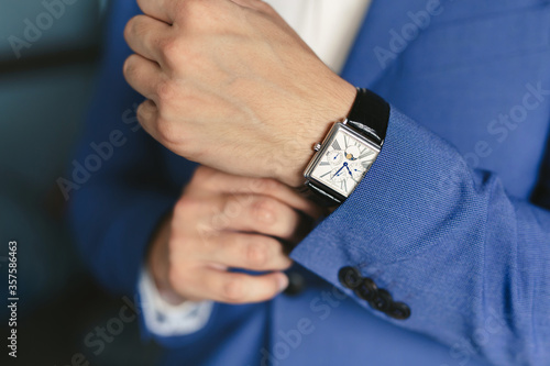 Close-up hands of the groom  with a clock