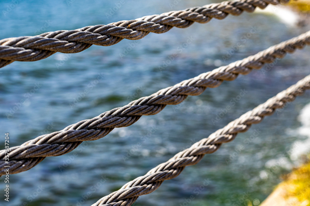 close up steel rope at beach and sea. grey cord. close up steel rope at beach and sea. grey cord.