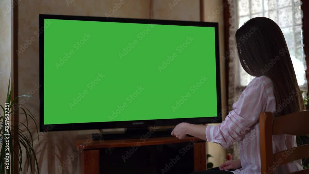 Watching modern television at home, girl changing TV channels with