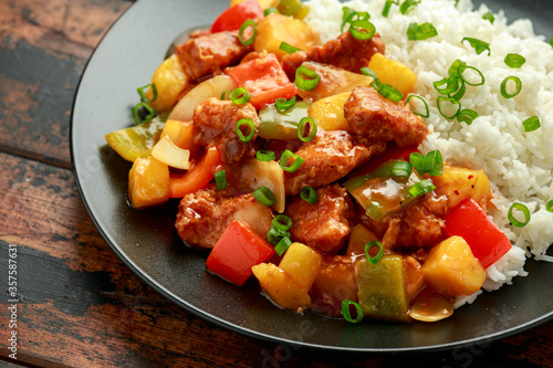 Pineapple and Chicken in sweet and sour sauce with bell pepper, rice and spring onion in black plate