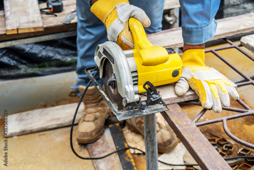 Carpenter using circular saw for cutting wooden boards with power tools, construction and home renovation, repair and construction tool