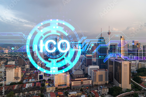 Hologram of glowing ICO icon, sunset panoramic city view of Kuala Lumpur. KL is the startup incubator of cryptocurrency projects in Malaysia, Asia. The concept of affordable opportunities in new era.